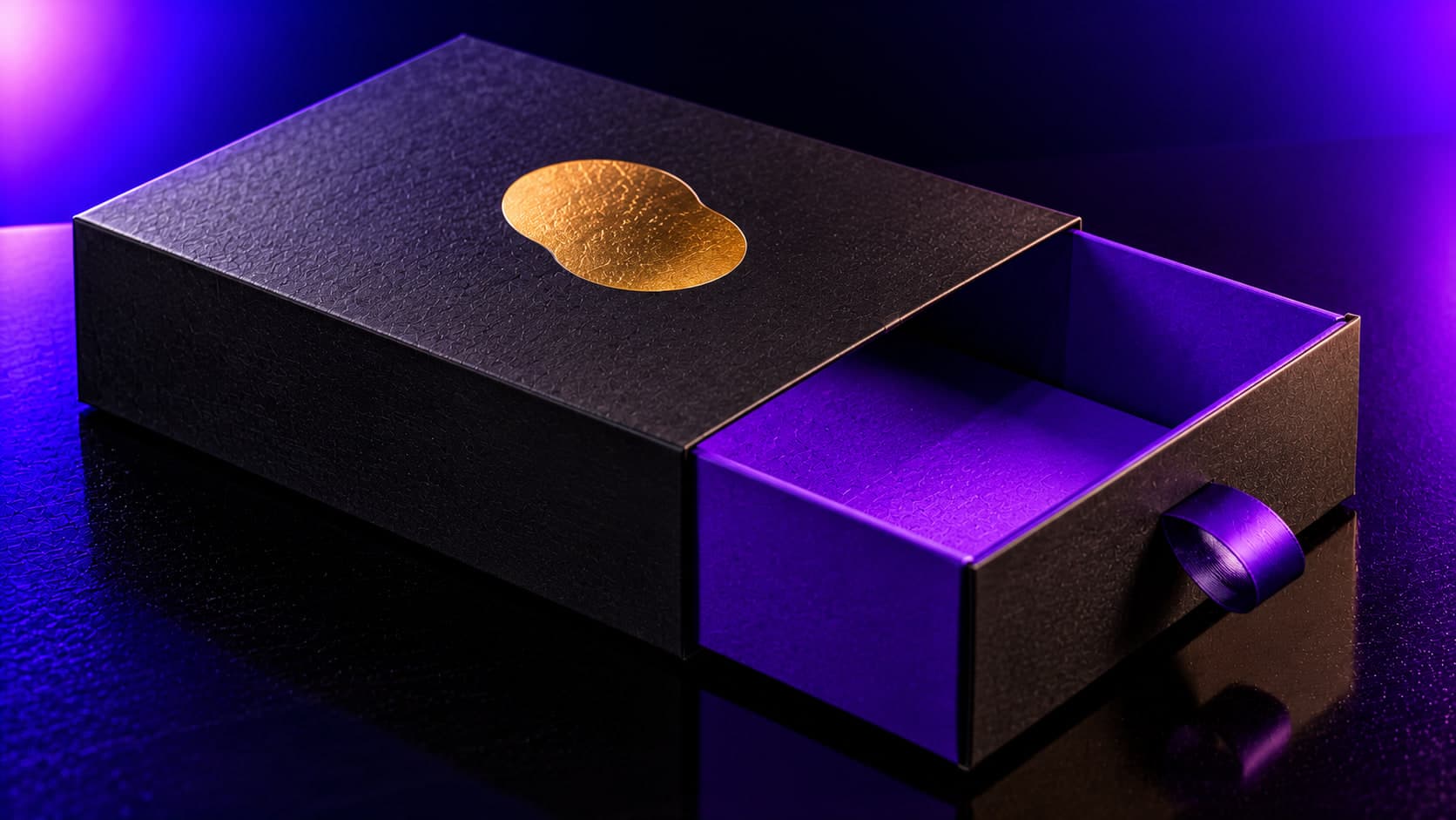 A black rigid drawer box with a gold foil mark, its violet-lined drawer pulled half open by a ribbon tab